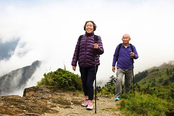 Asian senior couple hiking on mountain